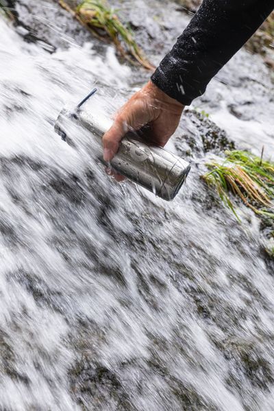 A hiker refilling their drinking water from a stream
