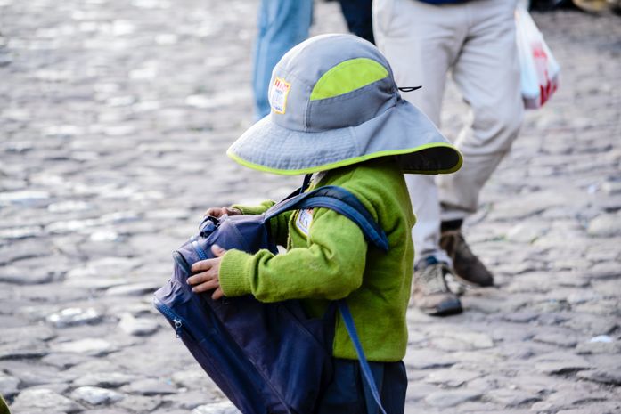 A kid carrying small belongings in a back pack
