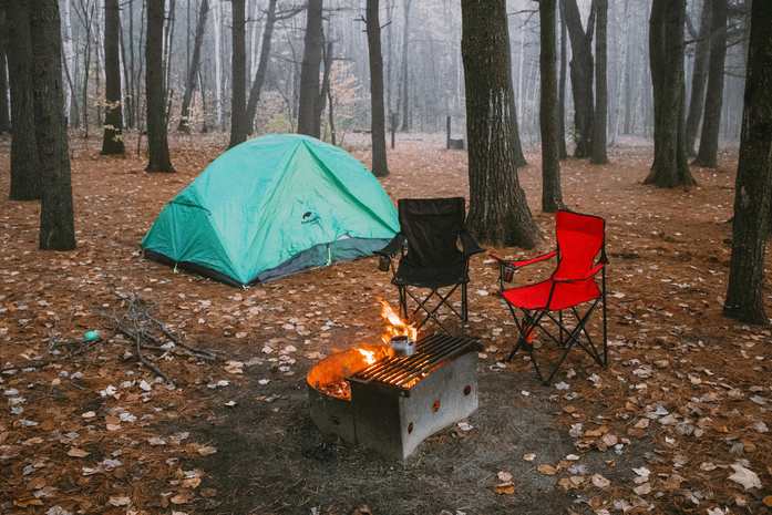 Camping chairs set out in front of a camp fireplace